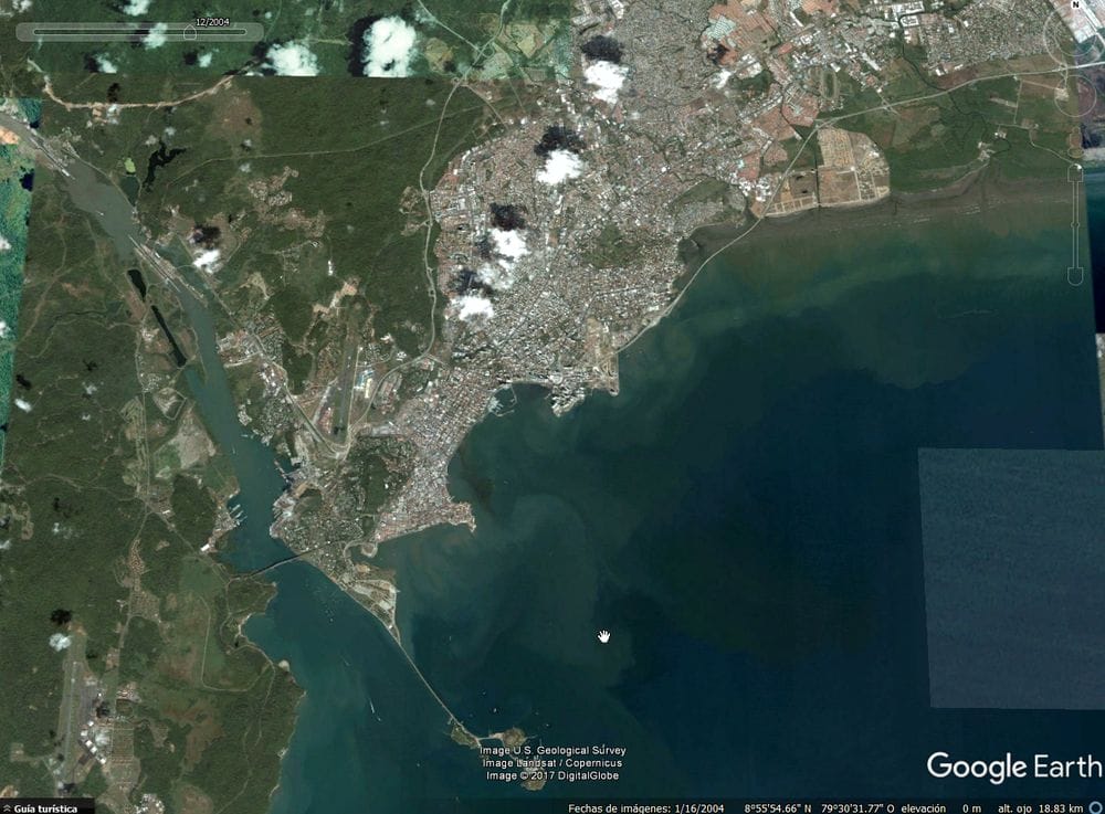 sittycia | OPORTUNIDADES DE NEGOCIO EN PANAMÁ Imagen satelital de una ciudad costera con áreas urbanas adyacentes a una gran bahía, con aguas cristalinas y diversos patrones de uso del suelo.