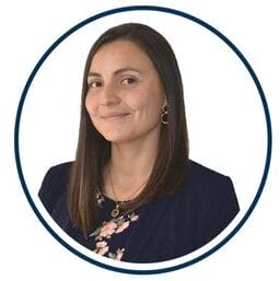 Foto profesional de una mujer con una chaqueta azul y un top floral, encerrada dentro de un marco circular, con el nombre "Ángela Vela" en la parte inferior y la etiqueta "Bitacora".