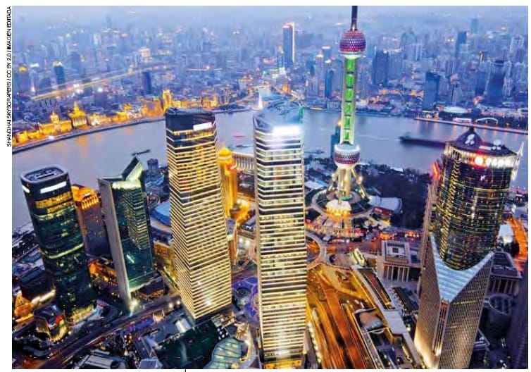 Vista aérea del horizonte de Shanghai al anochecer, con la torre de perlas orientales iluminada y los rascacielos circundantes.