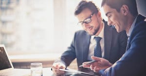 INICIO Dos hombres vestidos de negocios trabajando juntos con una computadora portátil y una tableta digital en una oficina.