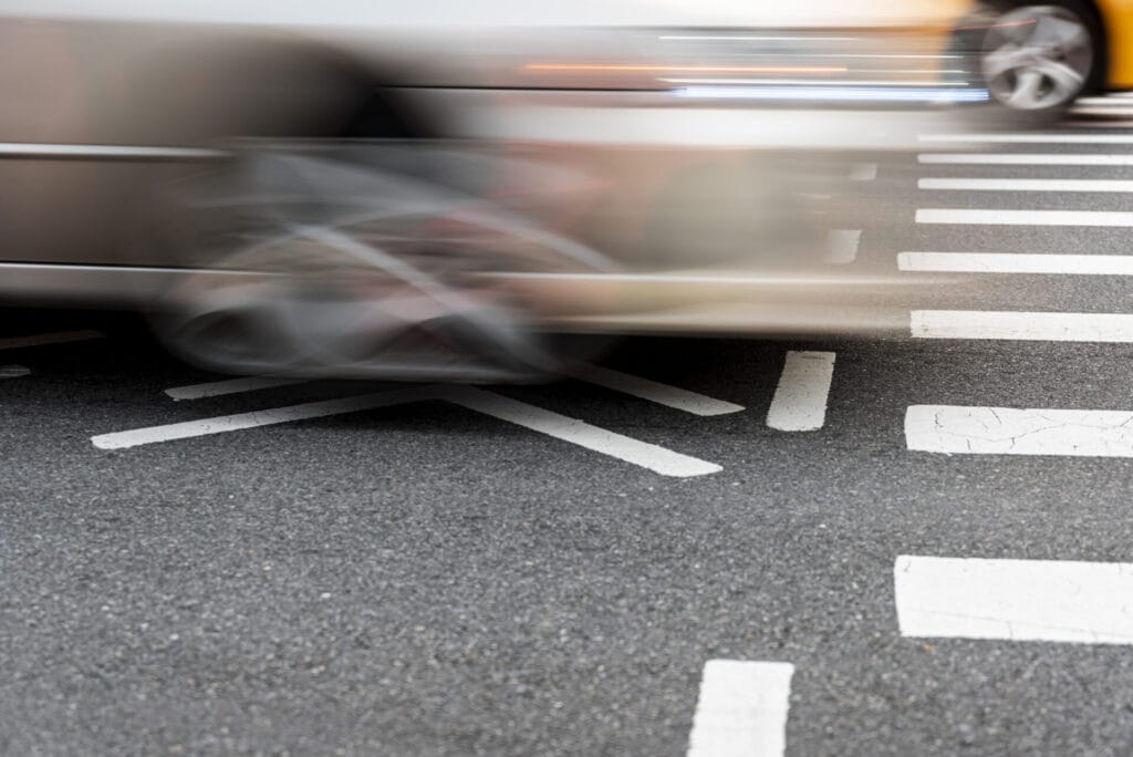 El movimiento borroso de los automóviles que cruzan un cruce de peatones en una carretera asfaltada resalta la problemática de la seguridad vial.